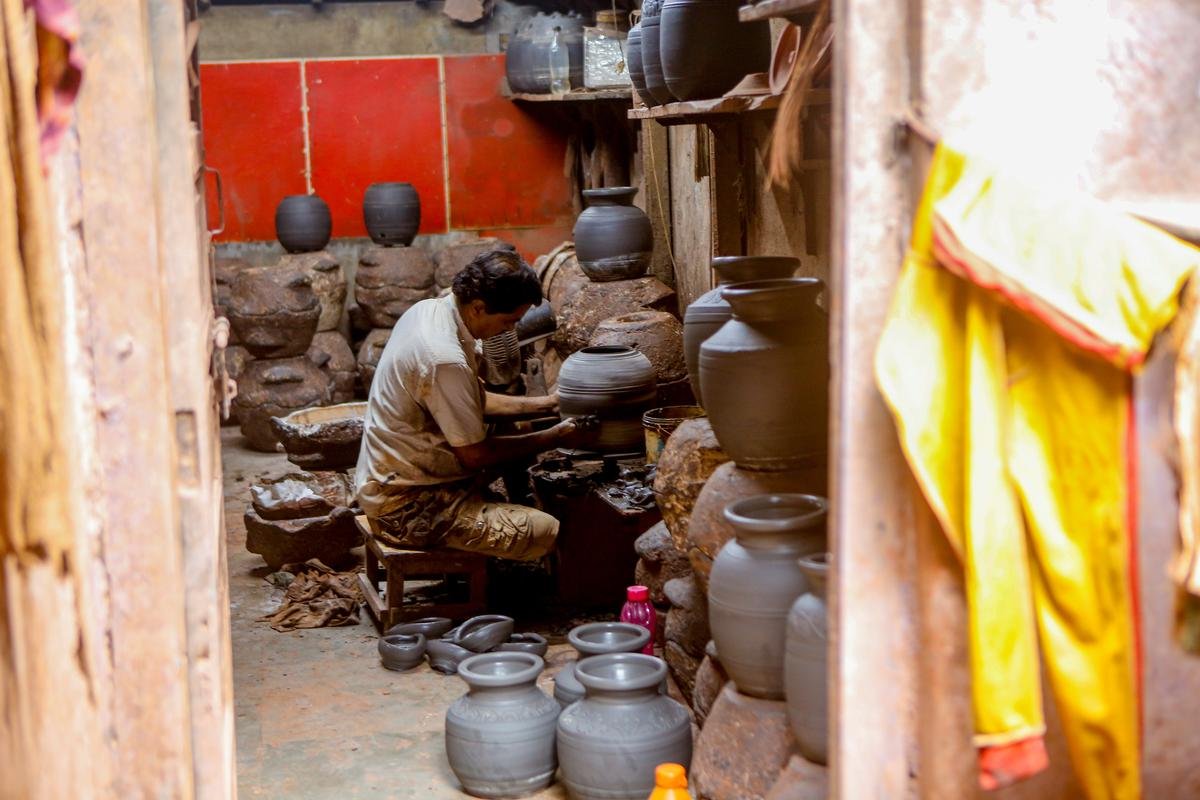 A man fashions an earthen pot at a potter’s wheel in Kumbharwada.