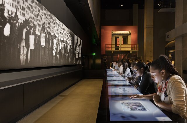 People sitting at the Segregation exhibit at The Smithsonian National Museum of African American History & Culture.