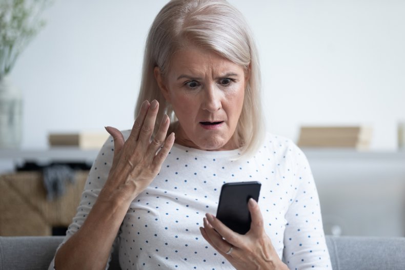 Older woman looking down furiously at smartphone