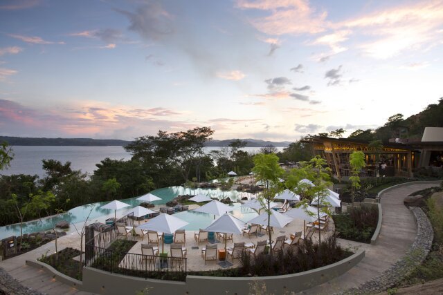 Chairs with umbrellas besides the pool at sunset at Andaz Costa Rica Resort at Peninsula Papagayo.