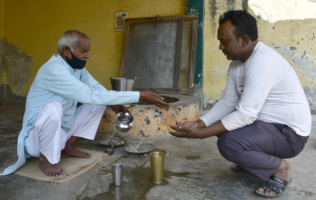 ‘Magic potion’: Sitaram Gangwar, 68, offers ‘miracle water’ from a well in his house in Hardua village, U.P., to Jagnnath Singh, a pakora seller, who sustained dog bites. R.V. MOORTHY