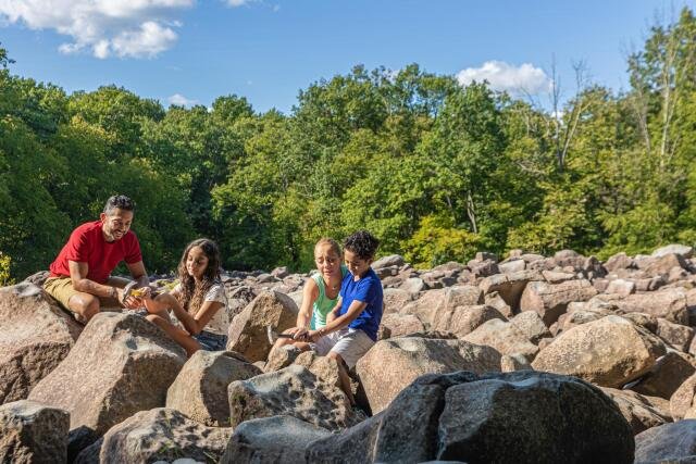 A family participates in hitting rocks at Ringing Rocks County Park