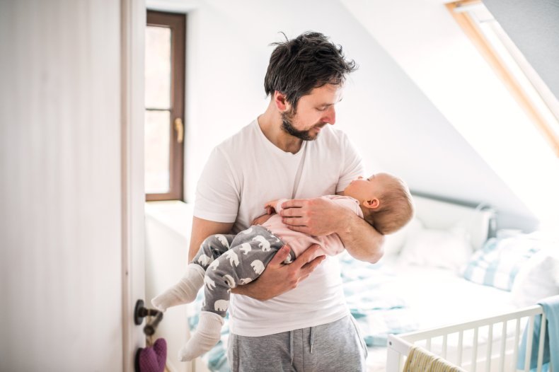 Man holding baby in arms at home.