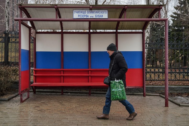 Man walks Russia flag bus stop Mariupol
