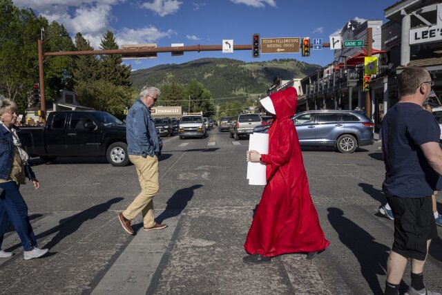 JACKSON HOLE, WYOMING - JUNE 24: Abortion rights protester Caitlin Devore, dressed as a "handmaiden" crosses a street to join a a gathering to protest the Supreme Court's decision in the Dobbs v Jackson Women's Health case on June 24, 2022 in Jackson Hole, Wyoming. Wyoming has a trigger law in place that will ban most abortions in the state five days after the governor certifies the ruling to the secretary of state. The Court's decision in the Dobbs v Jackson Women's Health case overturns the landmark 50-year-old Roe v Wade case, removing a federal right to an abortion.(Photo by Natalie Behring/Getty Images)